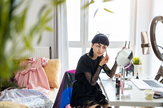 Young gender fluid person applying makeup at home
