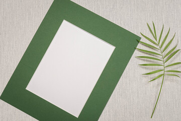 Cadre photo sur fond gris avec une feuille de plante verte. Pour écrire un message, invitation,...