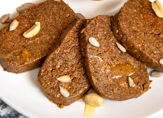 Homemade halva with peanuts and sunflowers with honey on a white plate