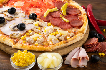 pizza and pizza ingredients. Olives, mushrooms, salami, tomato, pineapple and pizza on a dark background