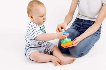 mother with her cute little baby playing with pyramid over white background