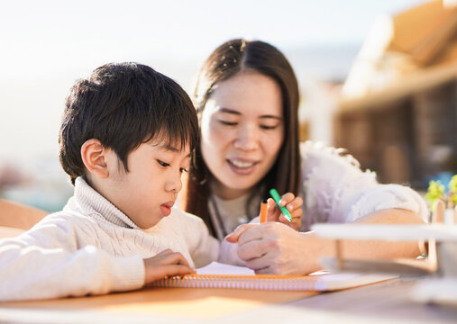 Asian mother doing drawing activities with little son outdoor on patio - Mother and child love
