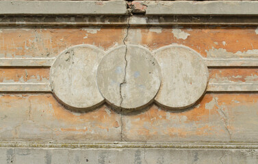 Concrete cracked pattern on the facade. three circles of stucco molding on the beige facade of the building with a crack. Architectural background for your design. Space for text