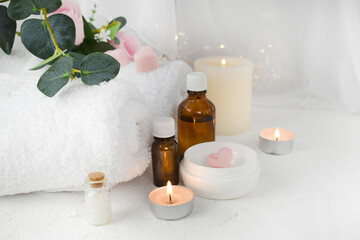 Fototapeta na wymiar Aromatherapy concept with essential oil bottle, body care cream, burning candles on light background. Spa resort wellness. Massage. Banner