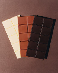 Variety of chocolate bars on brown background. Dark chocolate, milk chocolate, white chocolate