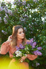 Young beautiful girl with a bouquet of lilacs. Walk in the fresh air. Freshness, spring and flowers concept.