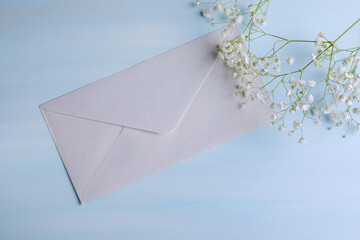 Festive greeting card with envelope in blue and white tones with text box. Green branch with delicate flowers.