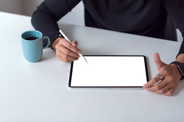 Image of a man using a tablet white blank screen with a pen and a coffee on the office table.