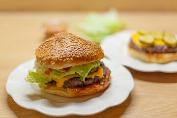 Process of cooking self made burgers at home. Cheesy burger on a white plate