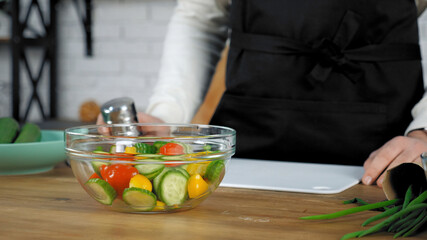 Fresh vegetables salad dish with cucumbers red cherry tomatoes yellow bell peppers in glass bowl, healthy eating food dieting and vegetarian concept