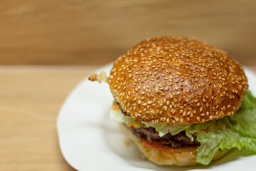 Juicy home made burger on a white plate with a wooden background