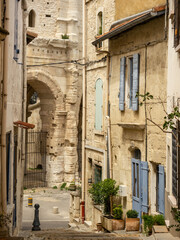 Fototapeta na wymiar Medieval street with sand colored walls of houses, leading to Amphitheater of Arles.