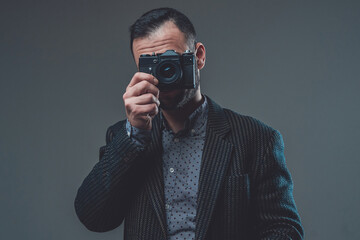 Modern digital camera. Front view of a middleaged guy wearing custom suit and doing shot with his...