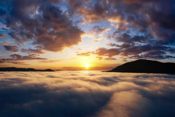 Beautiful sunrise in the mountains with dramatic sky over thick clouds.