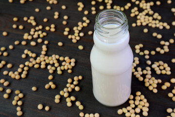 Bottle of Soy Milk Isolated on Black Wooden Table with Scattered Soy Beans