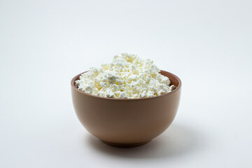 Cottage cheese on a white background. Homemade cottage cheese in a deep plate. Milk product