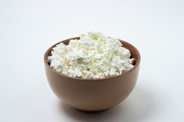 Cottage cheese on a white background. Homemade cottage cheese in a deep plate. Milk product