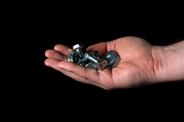 Man's hand holding or giving nuts and bolts on black isolated background