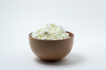 Cottage cheese on a white background. Homemade cottage cheese in a deep plate. Milk product