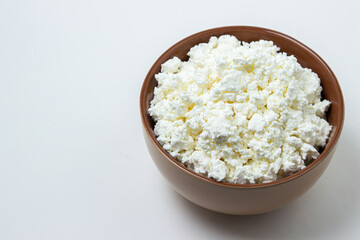 Cottage cheese on a white background. Homemade cottage cheese in a deep plate. Milk product