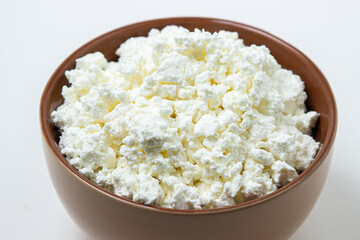 Cottage cheese on a white background. Homemade cottage cheese in a deep plate. Milk product