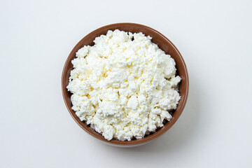 Cottage cheese on a white background. Homemade cottage cheese in a deep plate. Milk product