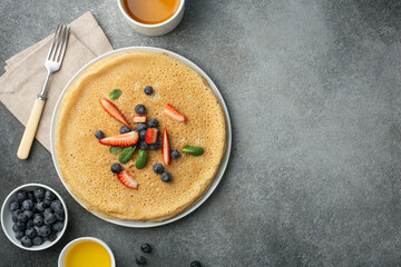 breakfast with pancakes with berries and honey, a cup of tea, top view