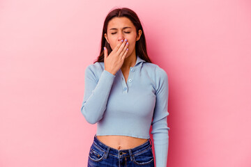 Young Indian woman isolated on pink background yawning showing a tired gesture covering mouth with hand.