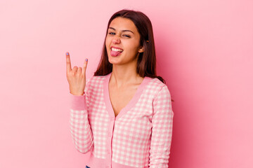 Young Indian woman isolated on pink background showing rock gesture with fingers