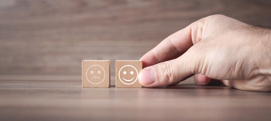 Man showing sad and happy smileys on wooden cube. Customer satisfaction