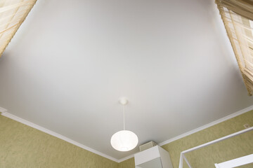 Stretch white matte ceiling close-up in the interior of a bedroom
