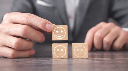 Man showing sad and happy smileys on wooden cube. Customer satisfaction