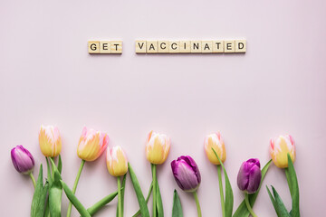 Tulips and text on pastel background, spring theme, flat lay, copy space, get vaccinated