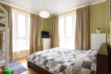 Interior of a bright bedroom with a large double bed and two large stained glass windows
