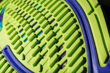 A sporty running shoe with a textured green sole on a black background.