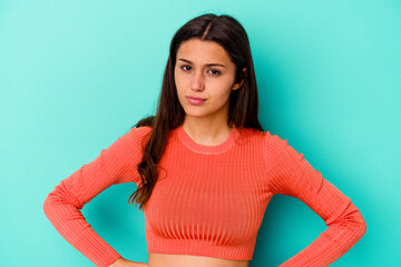 Young Indian woman isolated on blue background blows cheeks, has tired expression. Facial...