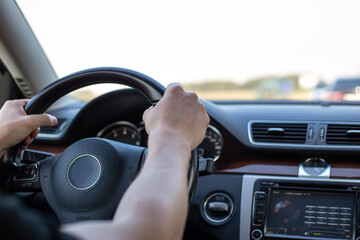 Driving vehicles. Male hands hold the steering wheel of a car, view from the inside of the cabin. Safety and attention on the road