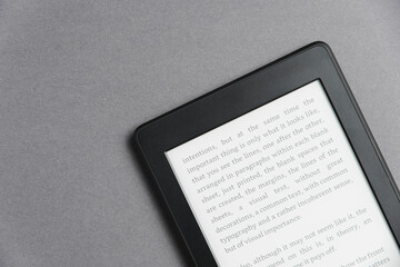 Closeup image of an electronic reader with text on the screen on a grey surface. Concepts of reading and technology.