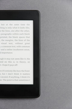 Closeup image of an electronic reader with text on the screen on a grey surface