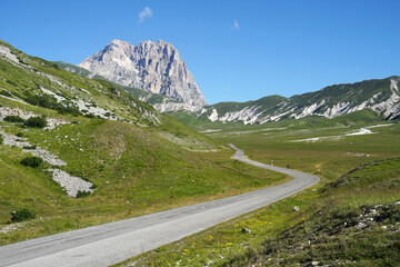 Road to Corno Grande Mountain, highest mountain of Apennine Mountains with grassy landscape, Gran Sasso National Park, Abruzzo, Italy, travel and climbing concept