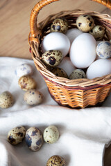 Quail and chicken eggs in a basket. Spring time. Easter composition on a wood background. Quail...
