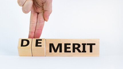 Demerit or merit symbol. Businessman turns wooden cubes and changes words 'demerit' to 'merit'. Beautiful white background, copy space. Business and demerit or merit concept.