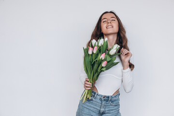 Image of screaming excited beautiful young woman standing isolated holding tulips flowers. 