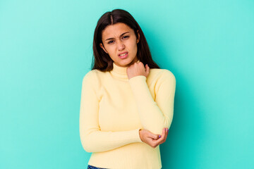 Obraz premium Young Indian woman isolated on blue background massaging elbow, suffering after a bad movement.