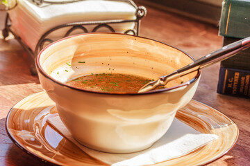 Delicious soup in a beige ceramic bowl on a wooden table. Side view, stock photo