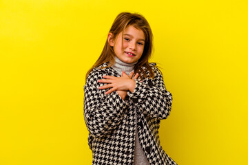 Little caucasian girl isolated on yellow background has friendly expression, pressing palm to chest. Love concept.