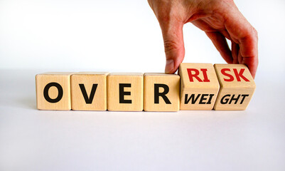 High risk from overweight symbol. Doctor turns wooden cubes and changes the words overweight to over risk. Beautiful white background, copy space. Medical and high risk from overweight concept.