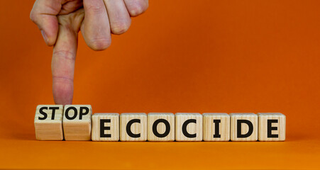 Stop ecocide symbol. Businessman turns wooden cubes and changes words ecocide to stop ecocide. Beautiful orange background, copy space. Business, ecological and stop ecocide concept.