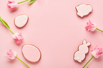 Easter greeting card with easter gingerbread eggs and tulip flowers over pink background. Top view flat lay with copy space