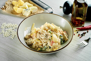 Classic Italian risotto with parmesan cheese, creamy sauce and vegetables, served in a white bowl on a wooden background. Restaurant food